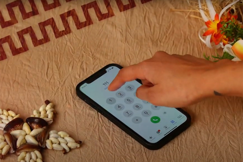 A screenshot from the video showing a hand dialing emergency services on a smartphone.