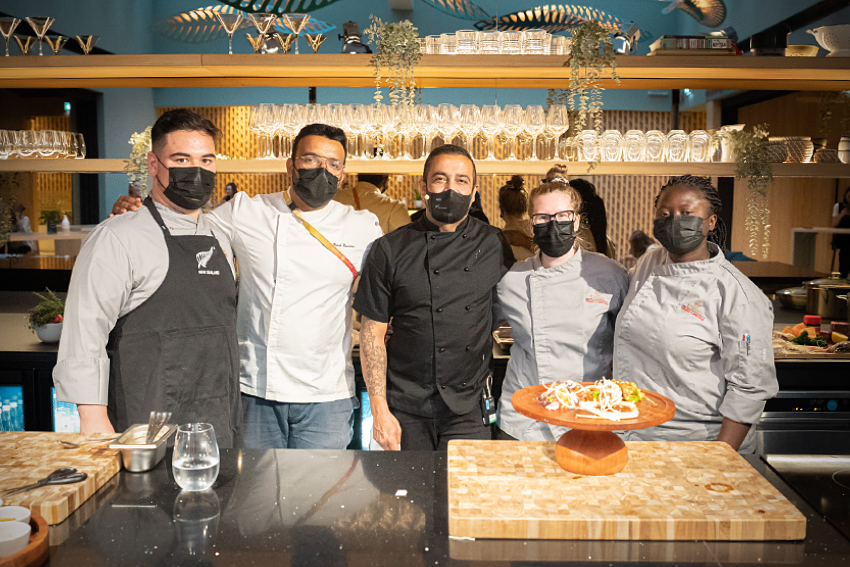 Wearing chef outfits and standing close to each other in a row: chefs Michael Lopesi, Rakesh Pillai, Sid Sahrawat, Laura-Jane Muller and Esther Olatunbosun