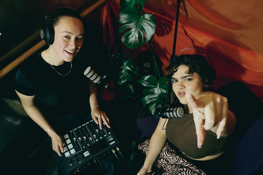 Two women recording with headphones and mixer